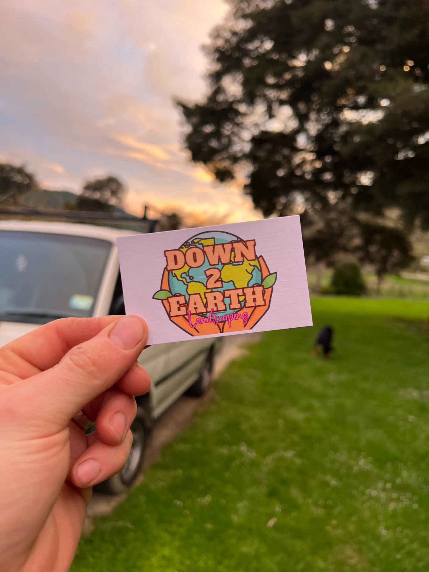 Down 2 Earth Nelson business card held at sunset on a rural property