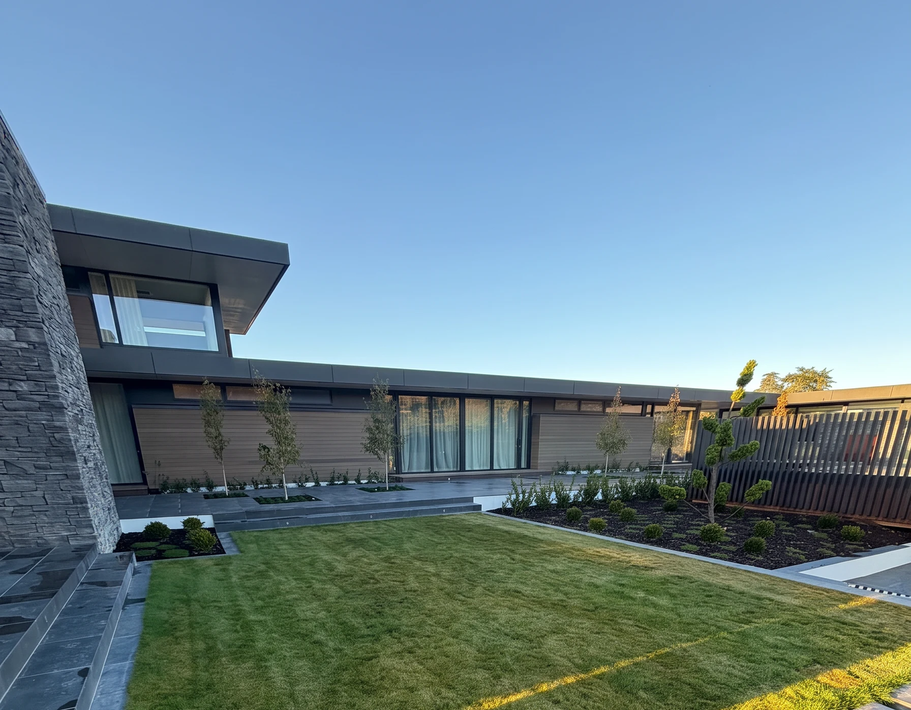 Instant lawn laid in a modern courtyard with stone steps and clipped planting